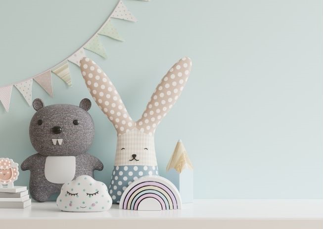 Stofftiere und Dekorationen auf einem Regal im Kinderzimmer mit einem Hasen, Biber und einer Regenbogen-Wolke.